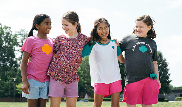 Group of younger girl scouts with arms around the shoulders and laughing 