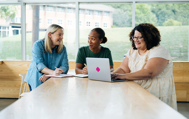 three Girl Scout Alum gathered around a computer