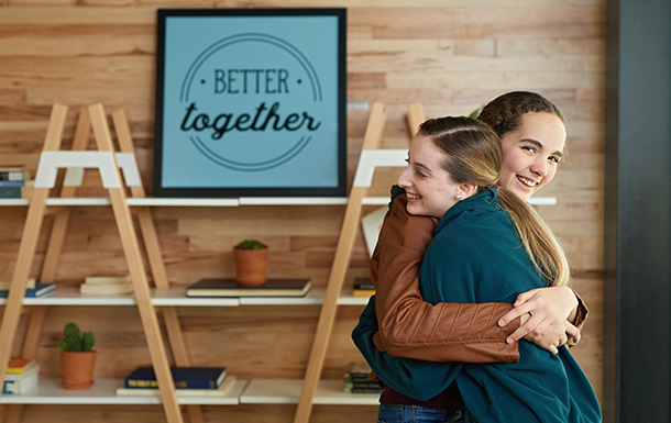 Two Ambassador Girl Scouts hugging and smiling