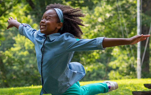 Brownie Girl Scout running and smiling outdoors